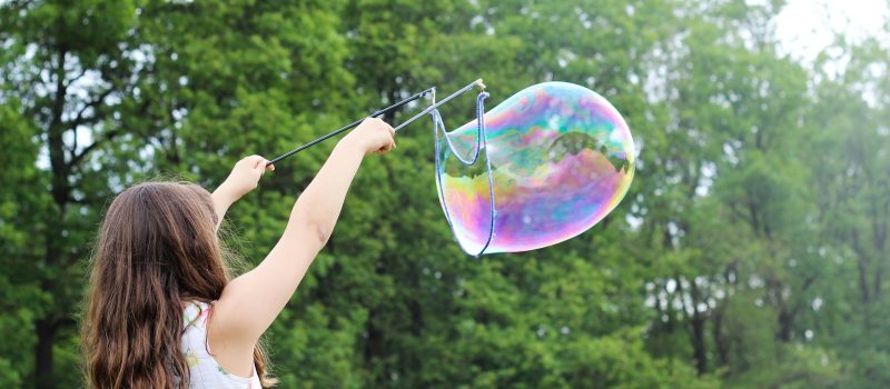 girl making bubbles during daytime